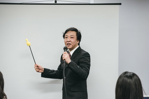 会議室でプレゼンテーションする上司、指示棒を持ちながら説明する場面