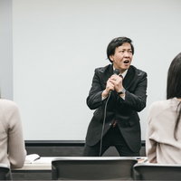 カラオケボックスで熱唱しはじめるスーツ姿の塾講師の写真