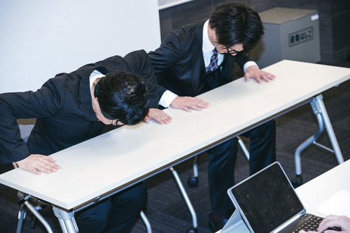 記者会見で報道陣に向かって謝罪する男性社員