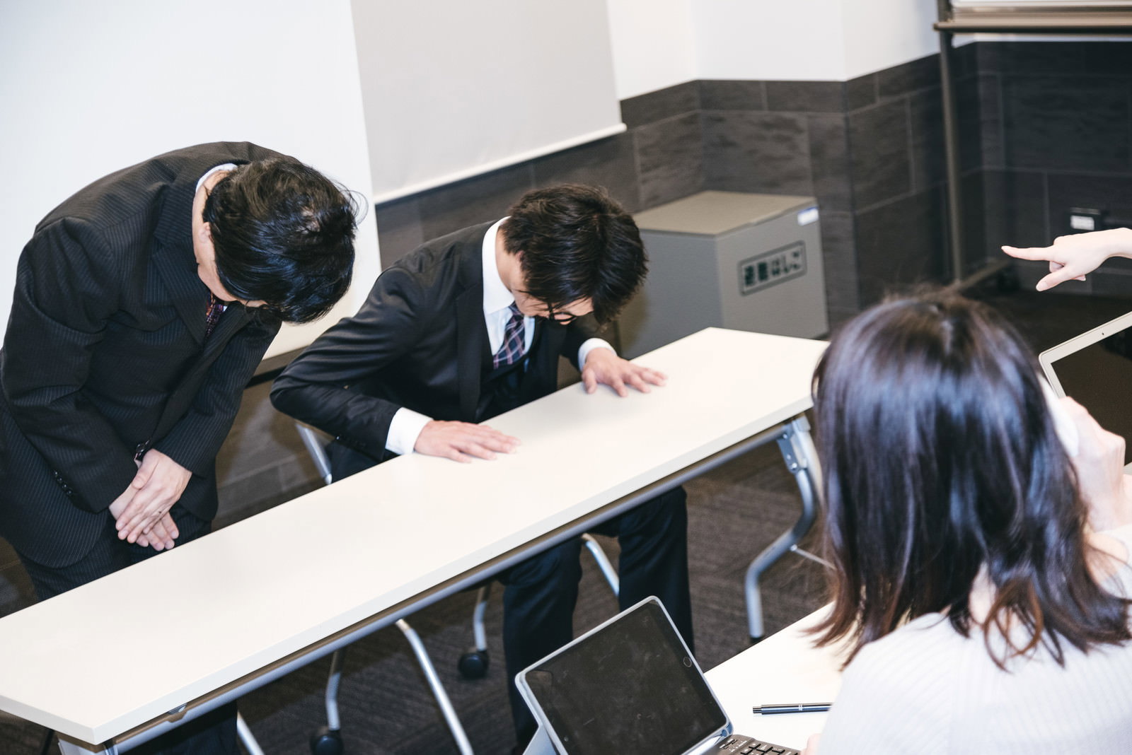 謝罪会見で深くお辞儀をするスーツ姿のビジネスマン［モデル：のせさん 村田裕章］