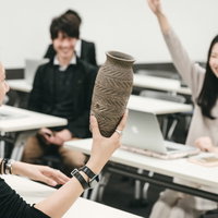 高額な壺を売るセンセイと最前列に座るサクラの女性の写真