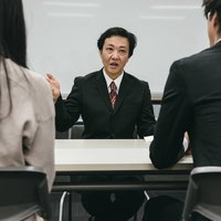 スーツを着た人事の男性による就活面接の書類確認の写真