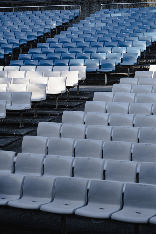 無観客のスタジアム観覧席で整然と並ぶ青いプラスチック座席