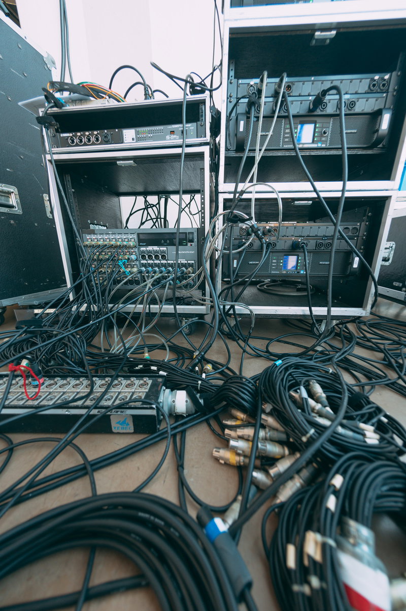 ラックに収納された音響機器と床に配線された多数のケーブル