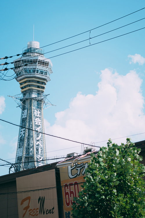 青空に白い雲と電線越しに見上げる通天閣の街角風景