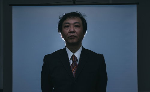 降霊中の部長、両手を広げて目を閉じ残業とリストラを表現