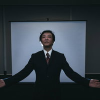スーツ姿の部長が両手を広げて怪しげなセミナーをはじめたの写真