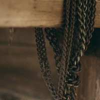 木製の柱に何重にも巻き付いた錆び付いたチェーンの写真