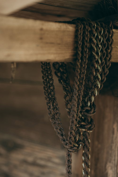 木製の柱に何重にも巻き付いた錆び付いたチェーン