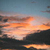 黒い雲とオレンジ色に染まる夕焼雲の美しい空のグラデーションの写真