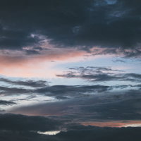 黒い雲から覗く青い空と夕焼けのグラデーションの写真