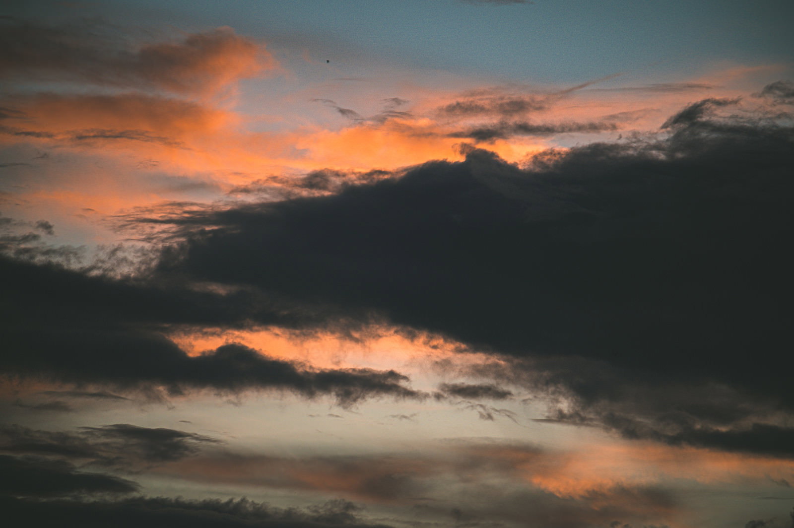 オレンジ色に焼けた夕空に黒い雲が浮かぶ夕焼けの風景