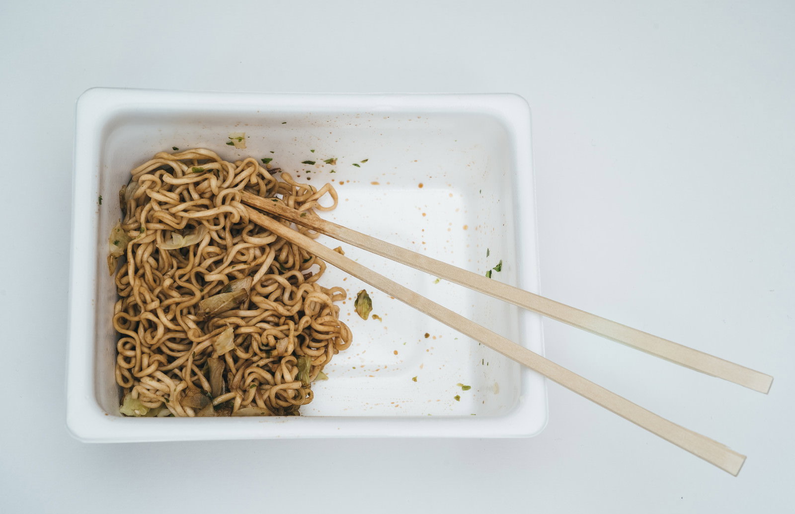 白いプラスチック容器に盛られた焼きそばと木製の箸