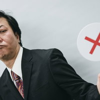 残念！不正解です、バツ印を掲げるスーツ姿の男性の写真