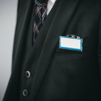 スーツに青いネームカードをつける会社員の胸元の写真