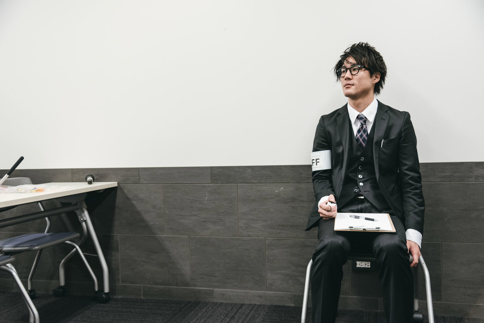 黒いスーツを着た男性スタッフがカウンターを持って人数を数えている［モデル：村田裕章］
