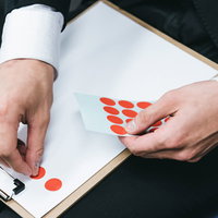 アンケート結果のシールを資料に貼る手のの写真