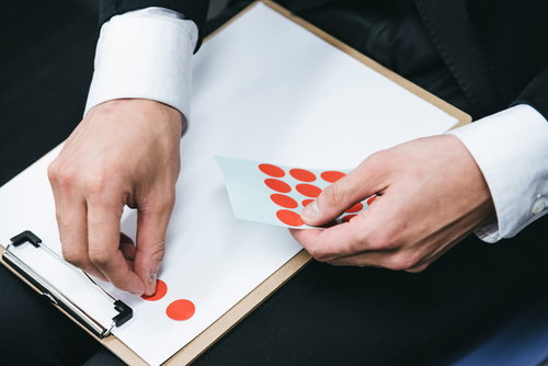 アンケート結果のシールを資料に貼る手の