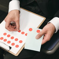 調査報告のシールを貼る手元と結果記録の写真