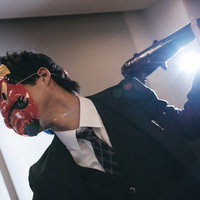 棍棒を振り上げた鬼役のスーツ姿の会社員（節分）の写真