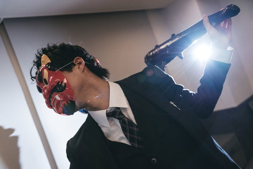 棍棒を振り上げた鬼役のスーツ姿の会社員（節分）