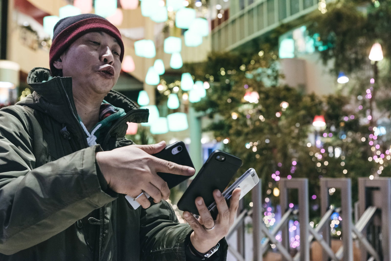 複数のスマートフォンを手に持ってゲームをプレイする男性［モデル：のせさん］