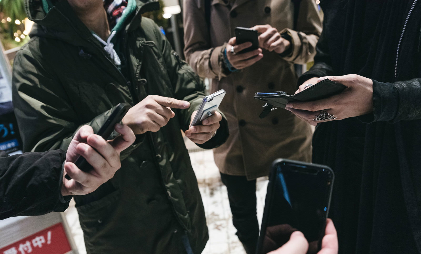 スマートフォンを手に持ちゲームに集中している複数の男性