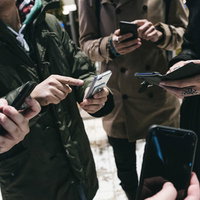 スマホでみんなで集まってレイドバトル、協力プレイを楽しむ男性グループの写真