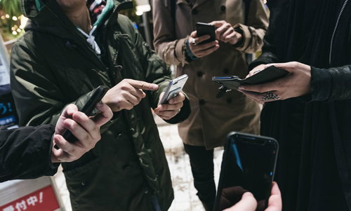 スマホでみんなで集まってレイドバトル、協力プレイを楽しむ男性グループ