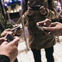 仲間と集まってスマホゲームをする男性たちの写真