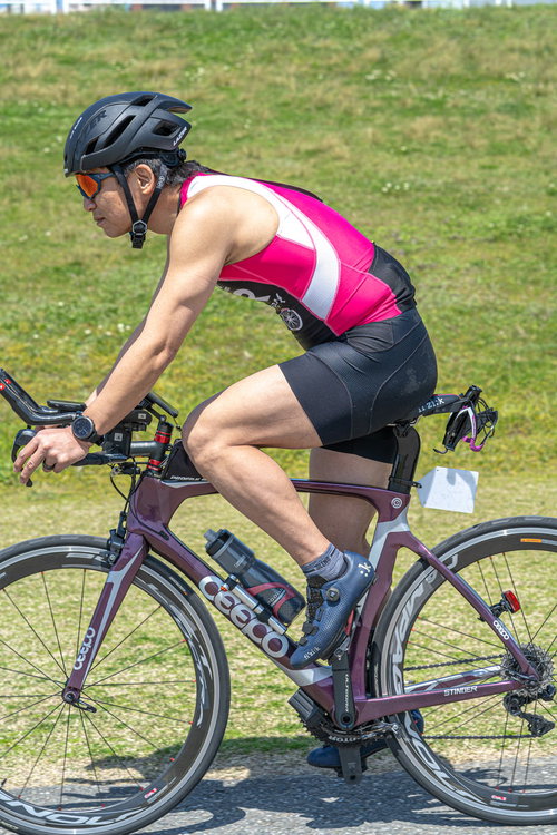 ピンクと黒のウェアのトライアスリートがロードバイクを運転する