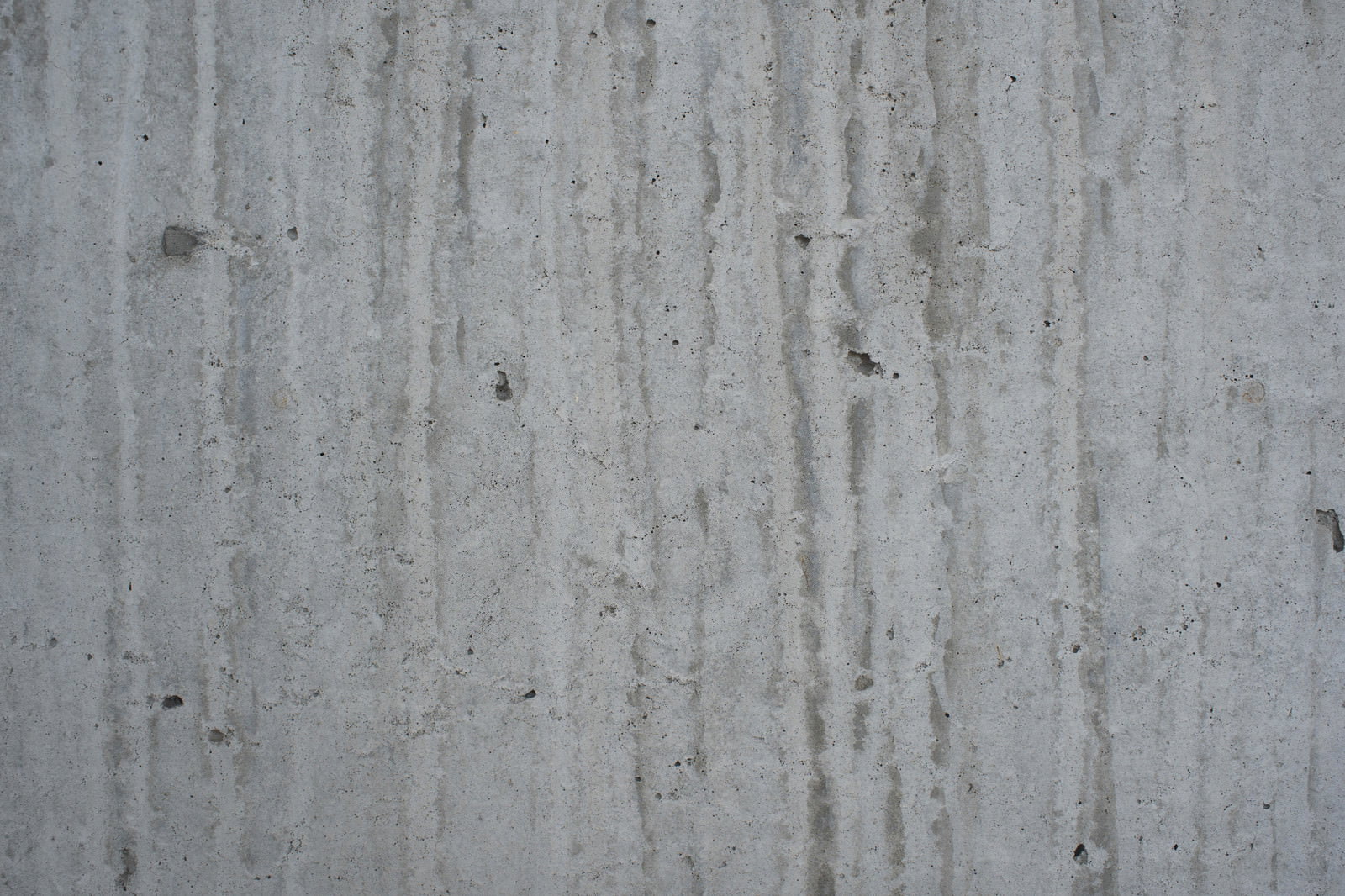 コンクリート壁に縦に流れる汚れと雨染みが見える劣化したテクスチャー