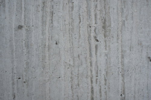 グレーのコンクリート壁に縦に流れる汚れと雨染みのテクスチャー
