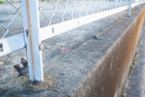 コンクリート段差上に設置された金属フェンスと有刺鉄線