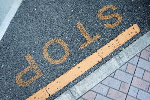 アスファルト道路に描かれたオレンジ色の停止線とSTOP文字