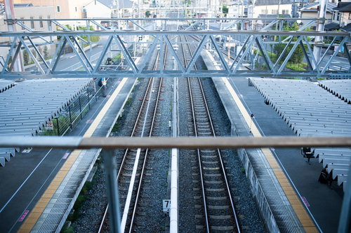 複数の線路が並ぶ無人の駅ホーム、広いプラットフォームと駅舎