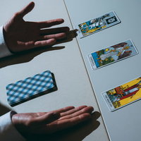 白いテーブルの上のタロットカードを両手で覆う占いの風景の写真