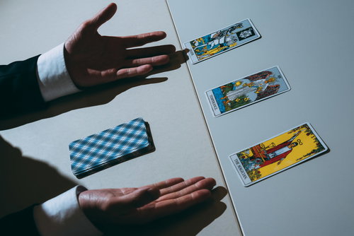 白いテーブルの上のタロットカードを両手で覆う占いの風景