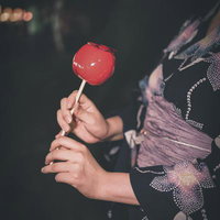 夜祭りで浴衣姿の子どもが持つ赤いりんごあめの写真