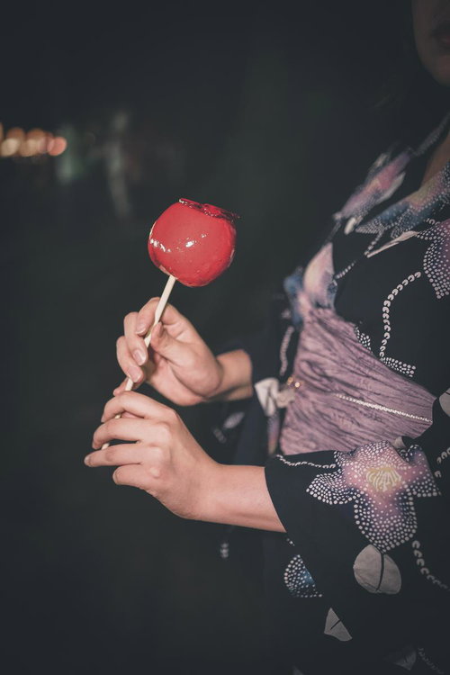 夜祭りで浴衣姿の子どもが持つ赤いりんごあめ