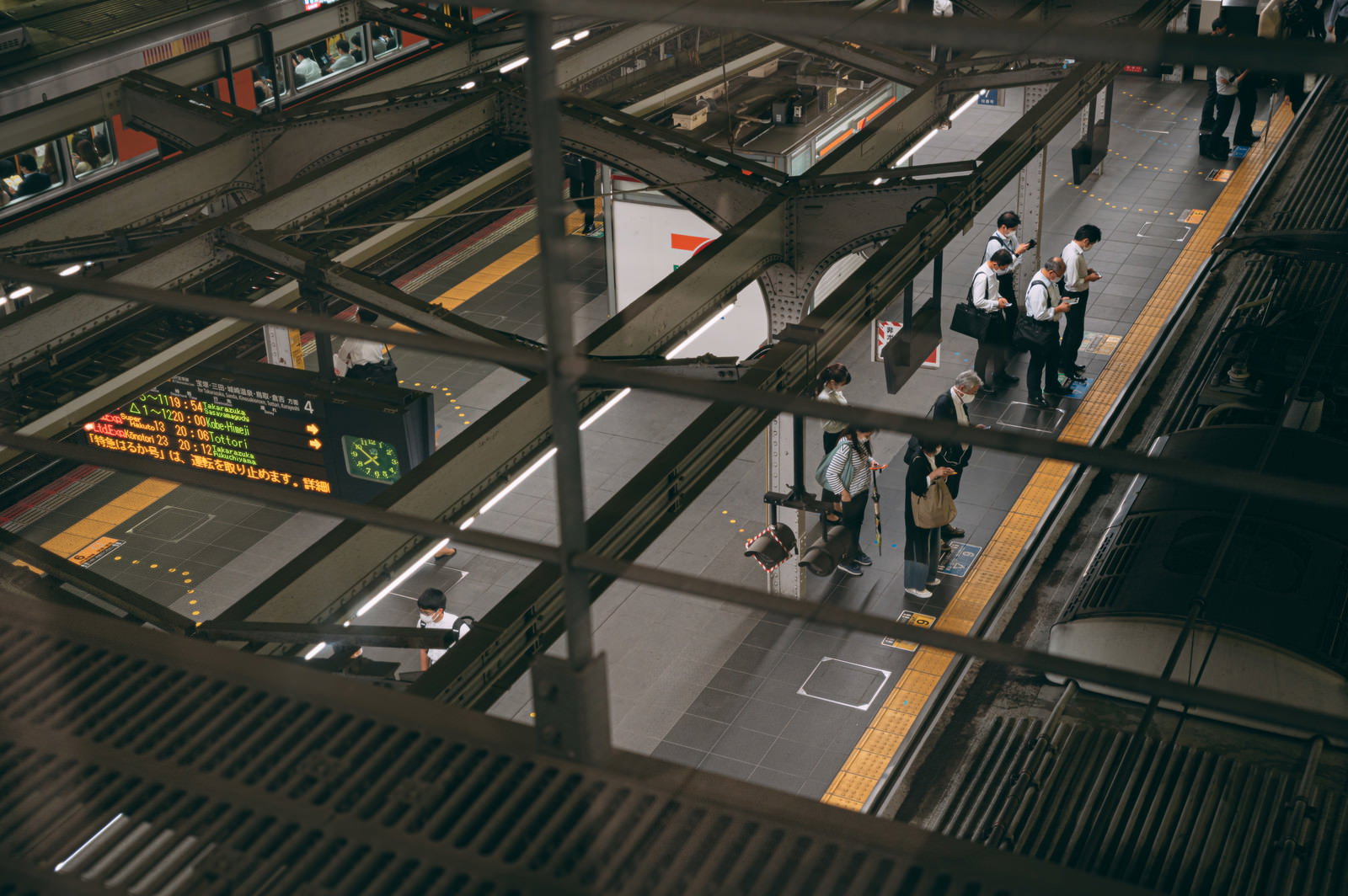 駅のホームで電車を待つために整列する通勤客たち