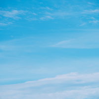 水色から白へグラデーションする空に薄い雲が浮かぶ風景の写真