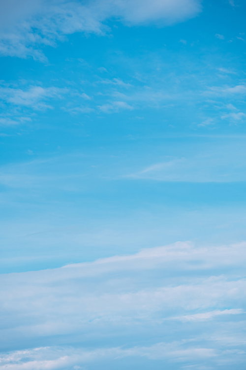 水色から白へグラデーションする空に薄い雲が浮かぶ風景