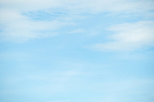 水色の空にぽっかり浮かぶ白い雲の晴天 背景