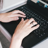 ノートパソコンのキーボードでタイピングする女性の手元の写真