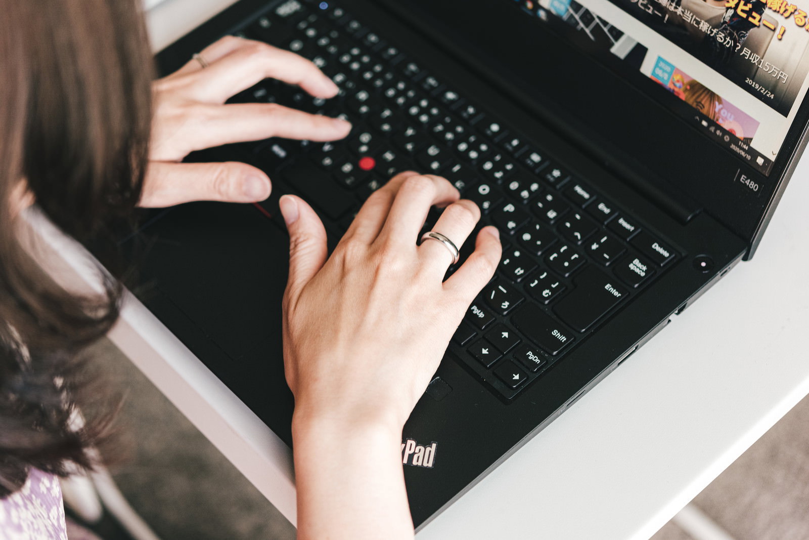 ノートパソコンのキーボードでタイピングする女性の手元