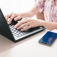 デスクでノートパソコンを使い在宅勤務する女性の写真