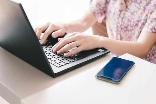 デスクでノートパソコンを使い在宅勤務する女性