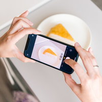 スマートフォンでチーズケーキを撮影中の手元の写真