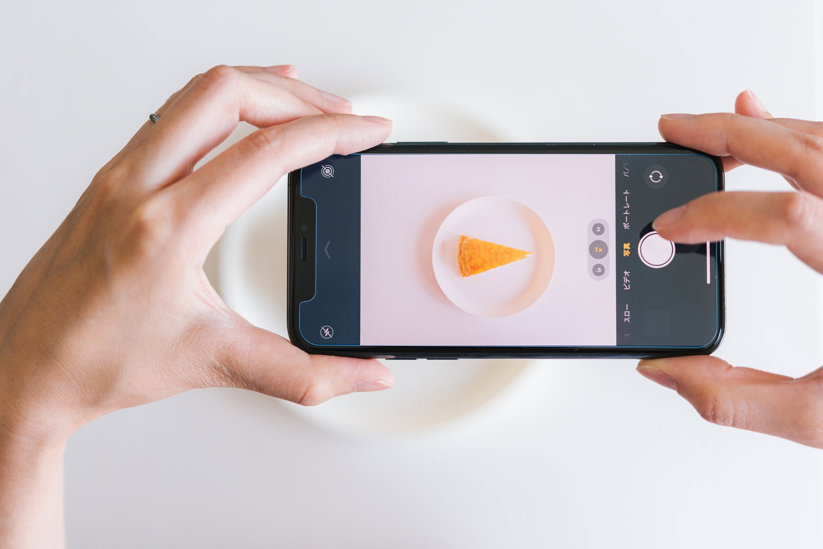 チーズケーキをスマホで撮影する女性の手